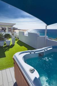 a swimming pool with an umbrella and the ocean at ALTAVISTA APARTAHOTEL-Adults Only over 14 in Morro del Jable