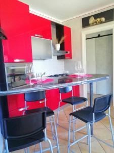 une cuisine avec des placards rouges et un bar avec des tabourets dans l'établissement Casa VistaLago Vertine, à Sulzano