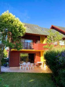 a house with a patio with tables and chairs at Casa en Condominio Foresta central y a 200 mt playa in Pucón