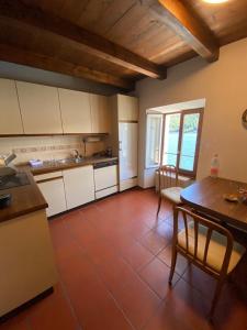 a kitchen with white cabinets and a red tile floor at Apartment in erster Seelinie in Morcote in Morcote