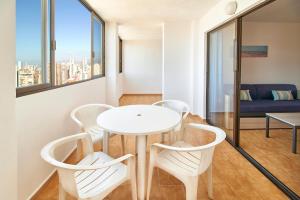 una mesa y sillas blancas en una habitación con ventana en Don Gregorio-Fincas Benidorm, en Benidorm