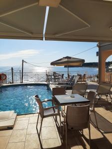 una piscina con mesas, sillas y una sombrilla en Corali Beach, en Tsilivi