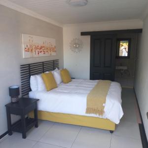 um quarto com uma grande cama branca com almofadas amarelas em Robert's Place Paarl em Paarl