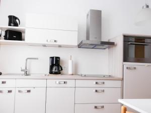 eine Küche mit weißen Schränken und einer Mikrowelle in der Unterkunft Haus Westwind Hallwegh 04 in Norderney
