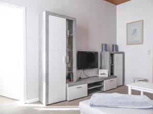 ein weißes Wohnzimmer mit einem TV und einem Schrank in der Unterkunft Haus Westwind Hallwegh 04 in Norderney