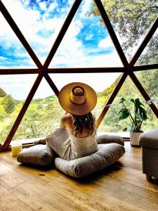 kobieta w kapeluszu siedząca na podłodze patrząca przez okno w obiekcie DomoCantabria w mieście Sobremazas