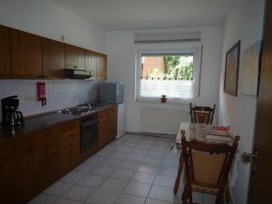 cocina con armarios de madera, mesa y ventana en Ferienzimmer Alte Kämpe, en Heede