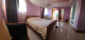 ein Schlafzimmer mit einem Bett in einem Zimmer mit lila Wänden in der Unterkunft Villa Jane in Arusha