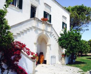 una casa bianca con fiori laterali di VILLA ENCANTAMIENTO Dimora Bouganville a Latiano