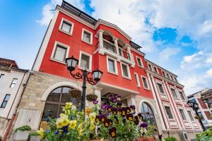 a red building with flowers in front of it at Real Hotel in Veliko Tŭrnovo