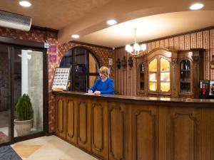 a woman standing at a bar in a restaurant at Real Hotel in Veliko Tŭrnovo