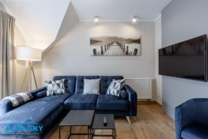 sala de estar con sofá azul y TV en Apartamenty BlueSky - Pusta 8 - blisko szlaków i wyciągów en Karpacz