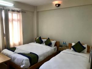 Duas camas num pequeno quarto com uma janela em Jacks Inn em Dhulikhel