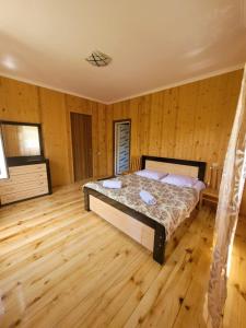 a bedroom with a bed in a room with wooden floors at Guesthouse Miranda in Ushguli