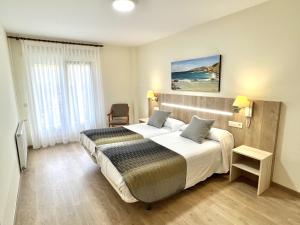 a hotel room with a large bed and a large window at Hotel Playa de Lago in Muxia