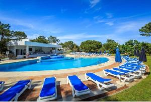 una piscina con tumbonas y sombrillas en Scarlet's Place - 1 bed Victory Village Quinta Do Lago - beach, nature, lakes en Quinta do Lago