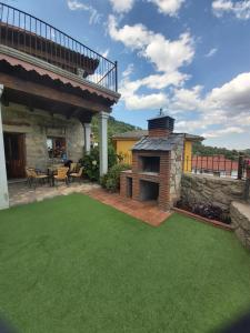 un patio trasero con chimenea de ladrillo y césped verde en Casa Rural Generoso, en Madroñal