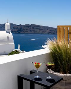 two drinks on a table on a balcony with the ocean at White Pearl Villas in Oia