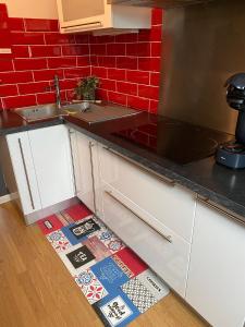 een keuken met een wastafel en een rode muur bij appartement romantique tout confort 4 personnes in Boulogne-sur-Mer