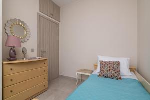 a bedroom with a bed and a dresser and a mirror at Emyria-Ground Floor Apartment in Zakynthos Town