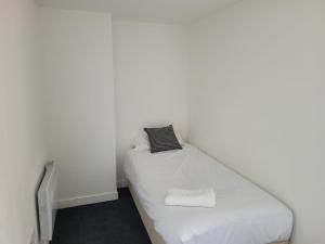 a small bedroom with a bed with white sheets at OYO Victoria Apartments in Middlesbrough