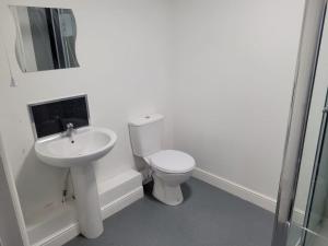 a white bathroom with a toilet and a sink at OYO Victoria Apartments in Middlesbrough
