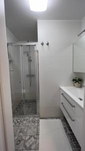 a white bathroom with a shower and a sink at Morski Val in Piran