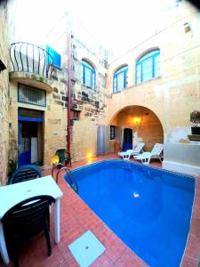 a large swimming pool with a table and chairs next to a building at Ta lucia farmhouse with private pool and BBQ in Santa Luċija