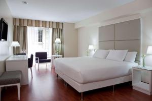ブエノスアイレスにあるNH ブエノス アイレス ラティーノのベッドルーム(白い大型ベッド1台、デスク付)