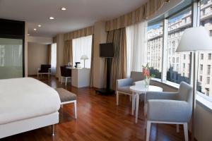 ブエノスアイレスにあるNH ブエノス アイレス ラティーノのベッド、テーブル、椅子が備わるホテルルームです。