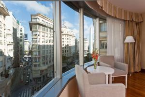 um quarto com uma mesa e cadeiras e uma grande janela em NH Buenos Aires Latino em Buenos Aires