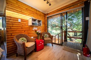 a room with two chairs and a table with a red suitcase at Windsong Living The Nest in Krugersdorp