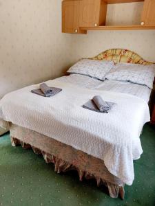a bed with a white blanket and two slippers on it at Domek holenderski Sosnowa in Wilkasy