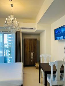 a bedroom with a bed and a table and a chandelier at Davao Boutique Condos - Inspiria Abreeza in Davao City