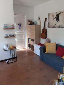 uma sala de estar com um sofá azul e uma guitarra em À la pause bien méritée =) em Villers-la-Ville