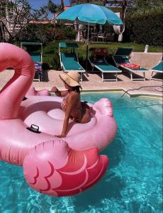 een vrouw met een hoed op een roze vlot in een zwembad bij Villa Grazia in Fondachello