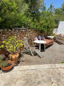 un patio con mesa, sillas y pared de piedra. en retreat studio en Santa Eularia des Riu