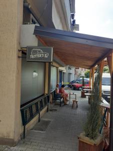 dos personas sentadas en un banco fuera de un restaurante en Porodicni apartman,Viktor cafee, en Šabac