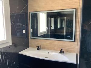 La salle de bains est pourvue d'un lavabo blanc et d'un miroir. dans l'établissement Wine Hôte Chambre d'hôtes, à Le Pian-Médoc