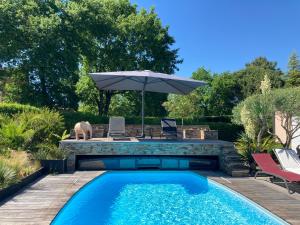 a swimming pool with an umbrella next to a patio at Wine Hôte Chambre d'hôtes in Le Pian-Médoc