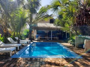 una piscina con palmeras y un complejo en Casa Malcampo, en Praia do Tofo