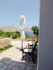 an umbrella and a bench next to a table and an umbrella at Kalypso apartment in Halki