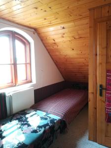 a bed in a room with a wooden ceiling at Kishalász Vendégház-Lovas in Lovas