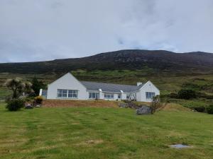 uma casa branca com uma colina ao fundo em Minaun Cliff View em Achill