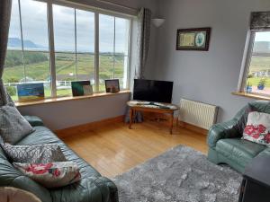 a living room with a couch and a table and windows at Minaun Cliff View in Achill