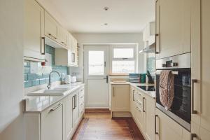 a kitchen with white cabinets and a wooden floor at Kingfisher Cottage 