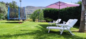 eine Gruppe Stühle und ein Regenschirm auf einem Hof in der Unterkunft Climiti Holiday House in Solarino