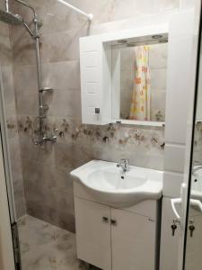 een badkamer met een wastafel, een douche en een spiegel bij В сърцето на Варна ви очаква прекрасен и просторен апартамент in Varna