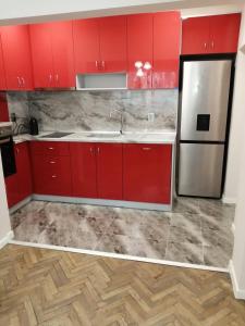 a kitchen with red cabinets and a stainless steel refrigerator at В сърцето на Варна ви очаква прекрасен и просторен апартамент in Varna City