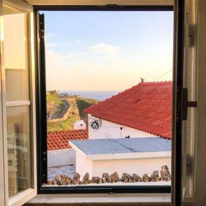 uma janela com vista para um edifício com telhado vermelho em Azenhas do Mar Cottage by Lisbon Dreams em Sintra
